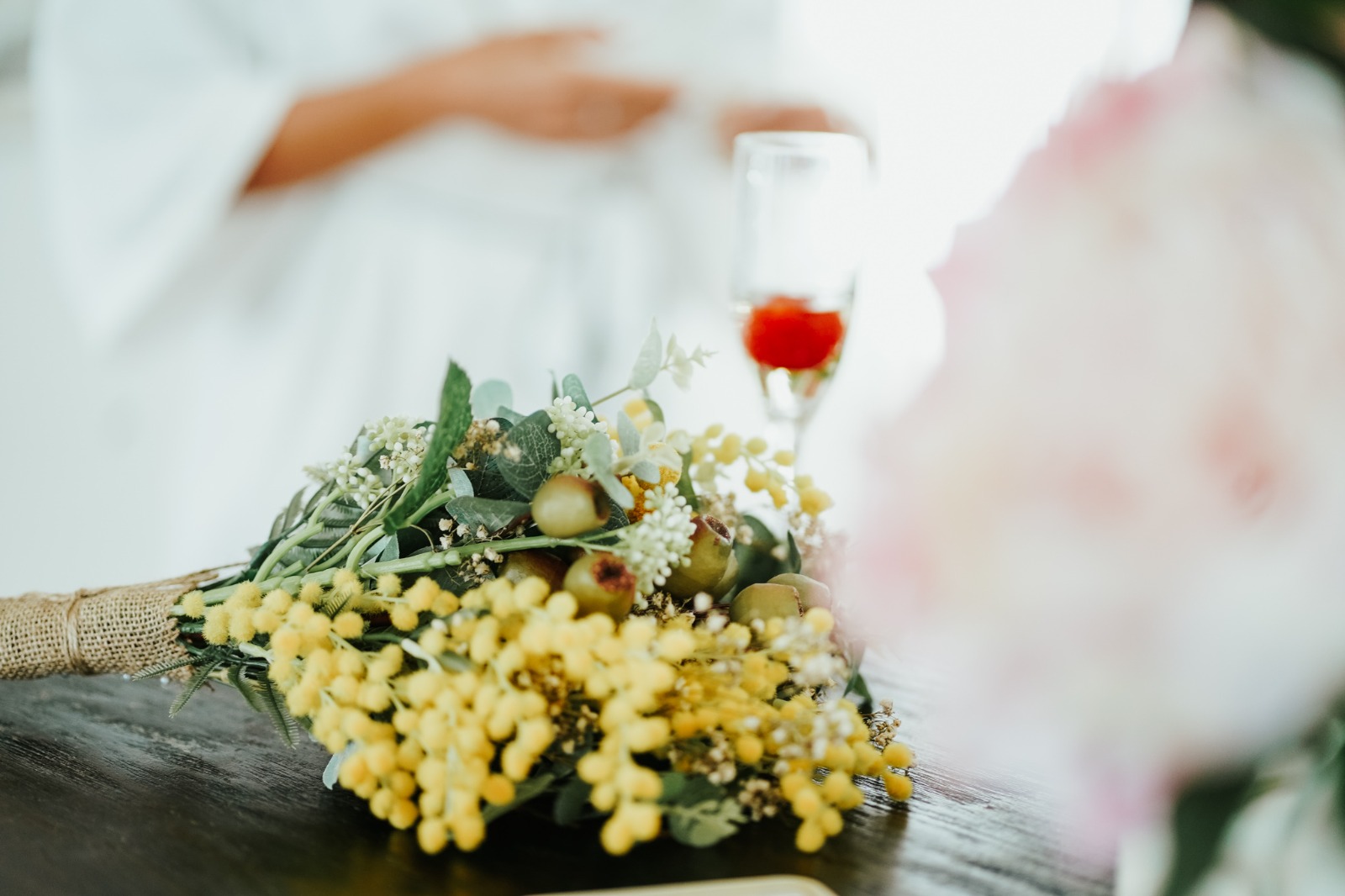 wedding bouquet of yellow flowers, wine glass on a tree stump, happy couple in background, Sydney Wedding